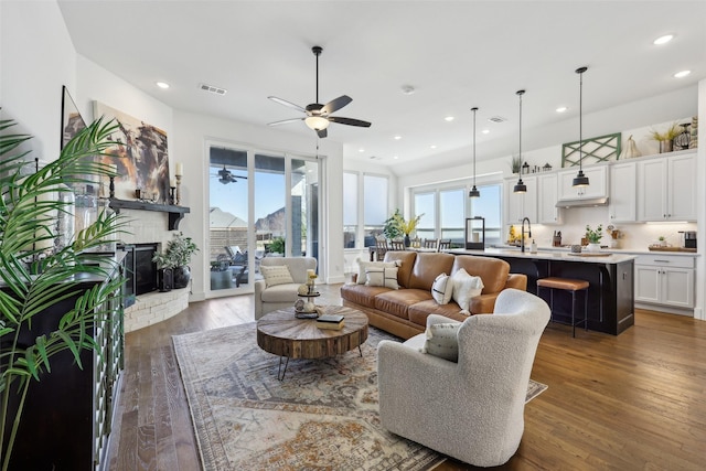 living area featuring ceiling fan, visible vents, a wealth of natural light, and wood finished floors