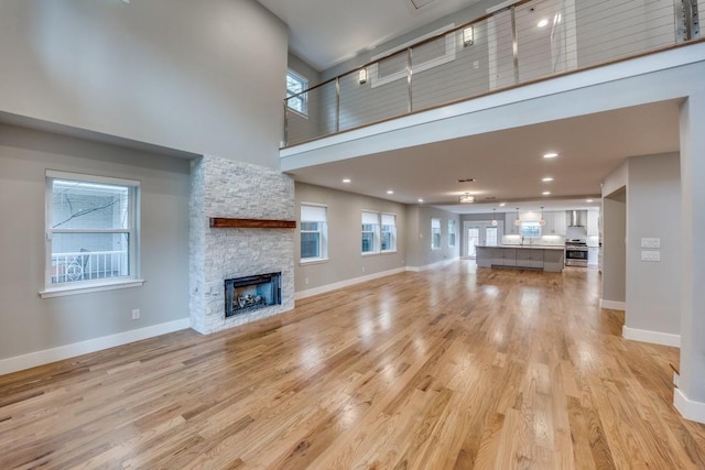 5120 Maple Springs Blvd, Dallas, TX 75235 - unfurnished living room featuring a towering ceiling, light wood-style floors, plenty of natural light, a fireplace, and recessed lighting