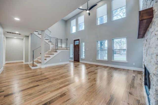 5120 Maple Springs Blvd, Dallas, TX 75235 - entrance foyer with stairs, a fireplace, a ceiling fan, light wood finished floors, and a towering ceiling