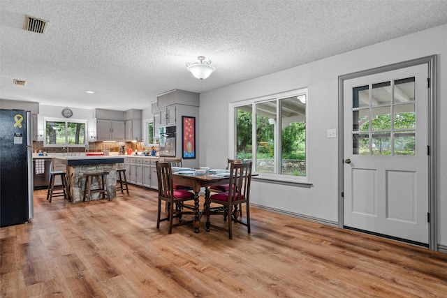 dining space featuring light wood-style floors, visible vents, and a textured ceiling