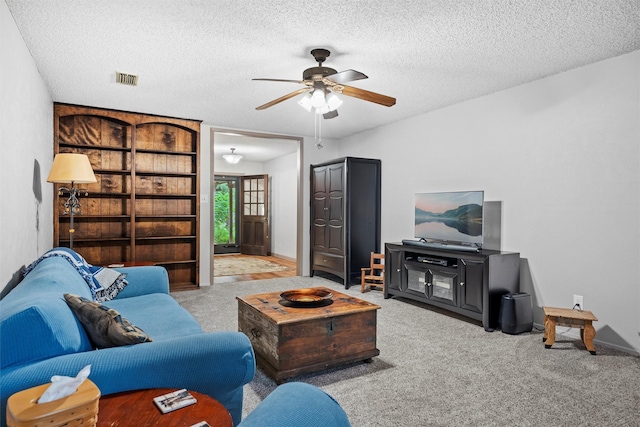 carpeted living room featuring a textured ceiling, baseboards, a ceiling fan, and visible vents