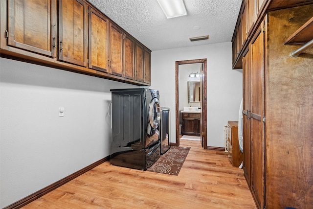 laundry area featuring independent washer and dryer, light wood-style floors, baseboards, and cabinet space