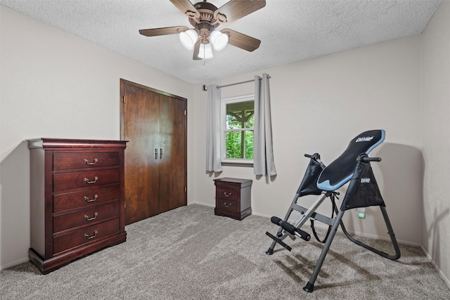exercise area featuring baseboards, carpet, a textured ceiling, and a ceiling fan
