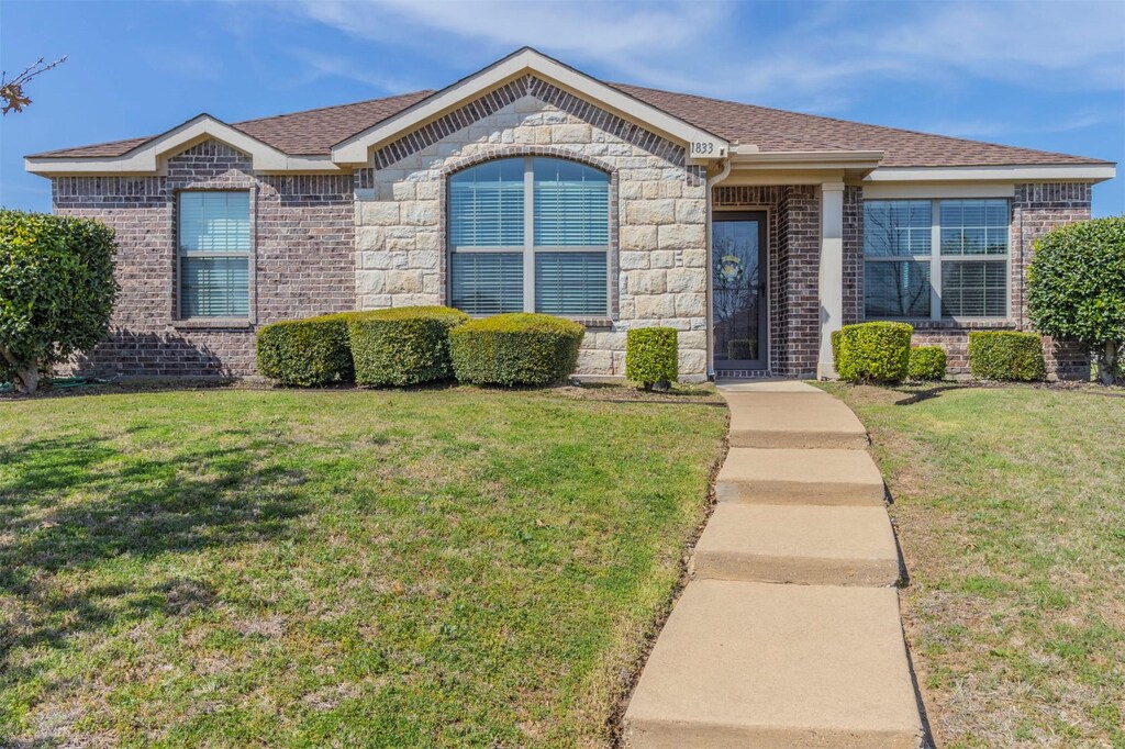 1833 Reynolds St, Lancaster, TX 75134 - view of front of property featuring stone siding, brick siding, roof with shingles, and a front yard