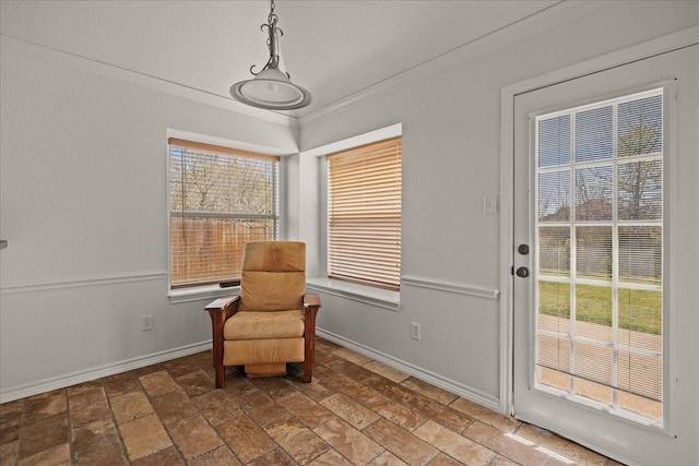 living area featuring crown molding, baseboards, and a wealth of natural light