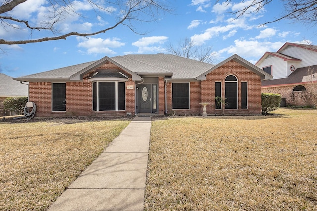 ranch-style house featuring roof with shingles, a front lawn, and brick siding