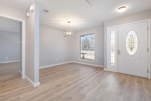 entrance foyer featuring visible vents, light wood finished floors, baseboards, and an inviting chandelier