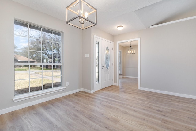 entryway featuring a healthy amount of sunlight, baseboards, light wood-style floors, and a chandelier