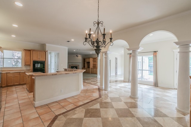 kitchen featuring a fireplace, open floor plan, a center island, and decorative columns