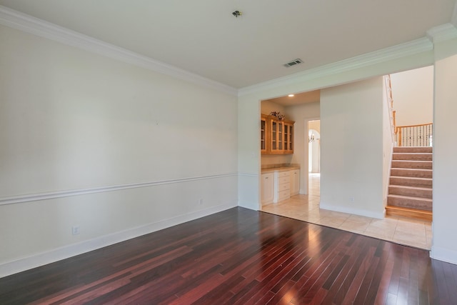 empty room featuring ornamental molding, visible vents, stairway, and light wood-style floors