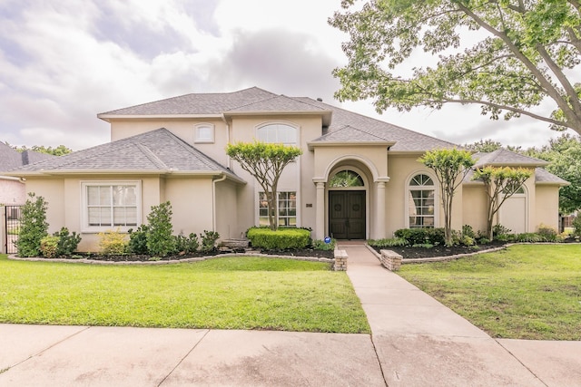 mediterranean / spanish house featuring a front lawn and stucco siding