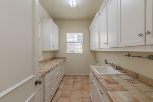 laundry area featuring hookup for a washing machine, electric dryer hookup, light tile patterned floors, cabinet space, and a sink