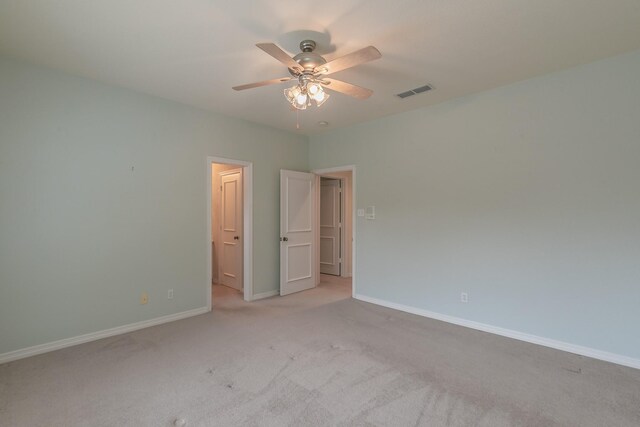 unfurnished bedroom featuring a ceiling fan, visible vents, light colored carpet, and baseboards