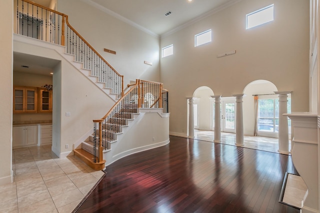 interior space with a high ceiling, hardwood / wood-style floors, and decorative columns