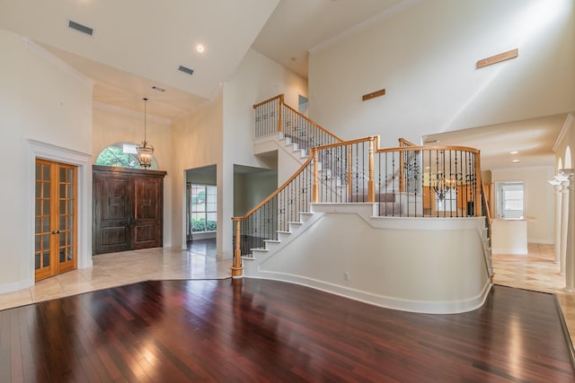 foyer entrance featuring a high ceiling, visible vents, hardwood / wood-style flooring, and baseboards