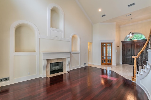 unfurnished living room with visible vents, high vaulted ceiling, a premium fireplace, and wood-type flooring
