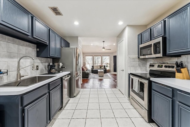 kitchen with backsplash, a sink, ceiling fan, visible vents, and appliances with stainless steel finishes