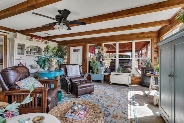 living room with wood finished floors, visible vents, beamed ceiling, and ceiling fan