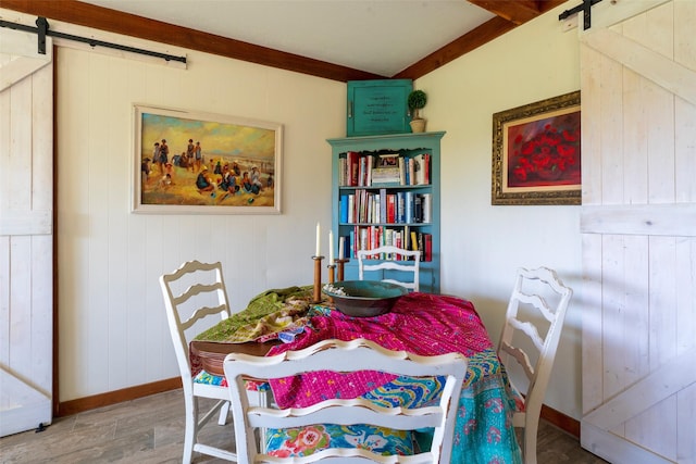 dining area featuring baseboards, a barn door, and wood finished floors