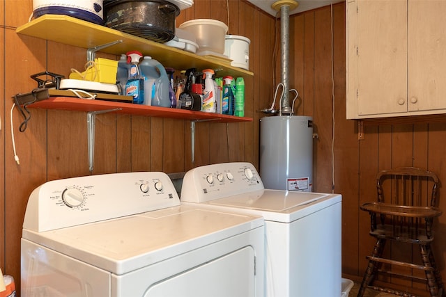 washroom featuring water heater, washer and dryer, and wood walls