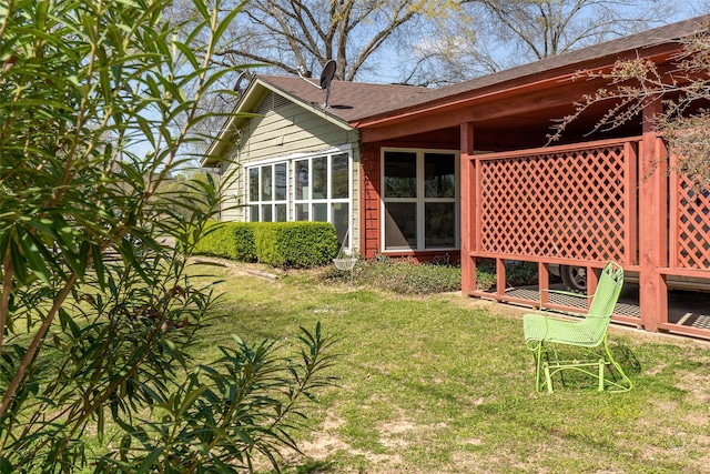 back of property featuring a lawn and a shingled roof