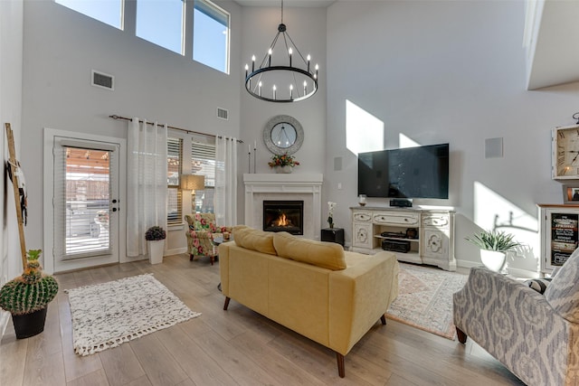 living room featuring beverage cooler, a high ceiling, an inviting chandelier, visible vents, and a glass covered fireplace