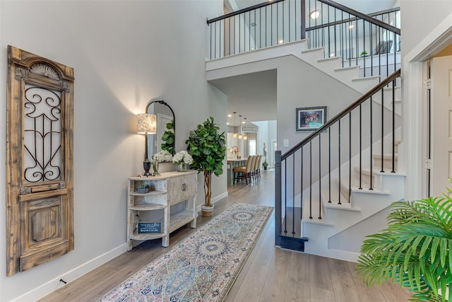 entryway featuring wood finished floors, a high ceiling, baseboards, and stairs