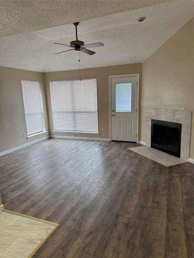unfurnished living room with baseboards, ceiling fan, wood finished floors, and a premium fireplace