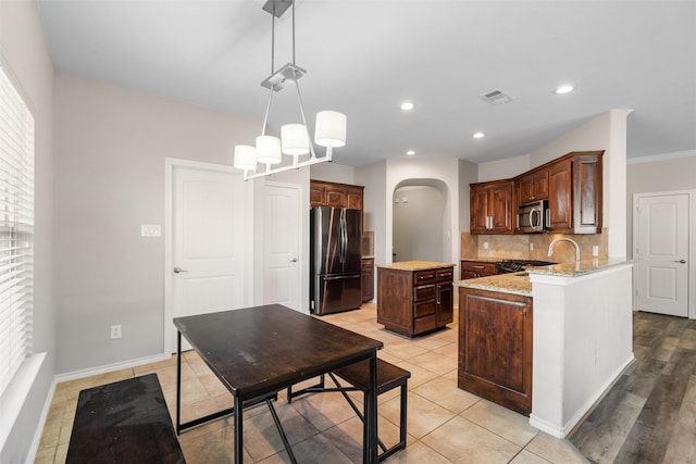 5532 Grayson Ridge Dr, Fort Worth, TX 76179 - kitchen with stainless steel appliances, arched walkways, a center island, light stone counters, and backsplash
