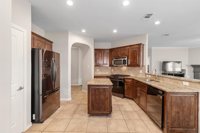 5532 Grayson Ridge Dr, Fort Worth, TX 76179 - kitchen with stainless steel appliances, a kitchen island, arched walkways, backsplash, and light stone countertops