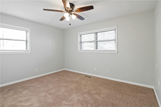 carpeted spare room with a ceiling fan, baseboards, and visible vents