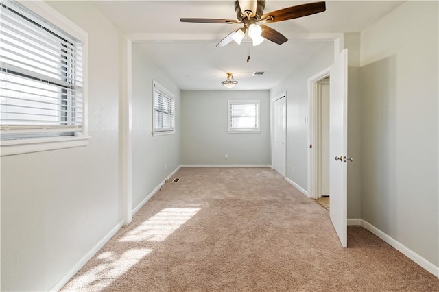 empty room with light carpet, baseboards, ceiling fan, and visible vents
