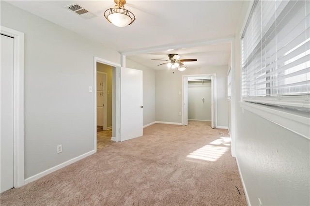 spare room with baseboards, carpet floors, visible vents, and a ceiling fan