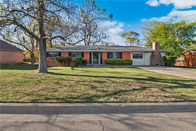 ranch-style home with a chimney, brick siding, driveway, and a front lawn