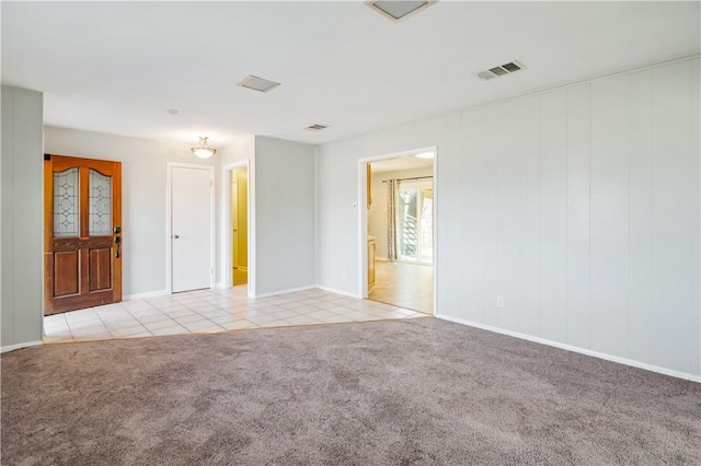empty room featuring light carpet, visible vents, and light tile patterned floors