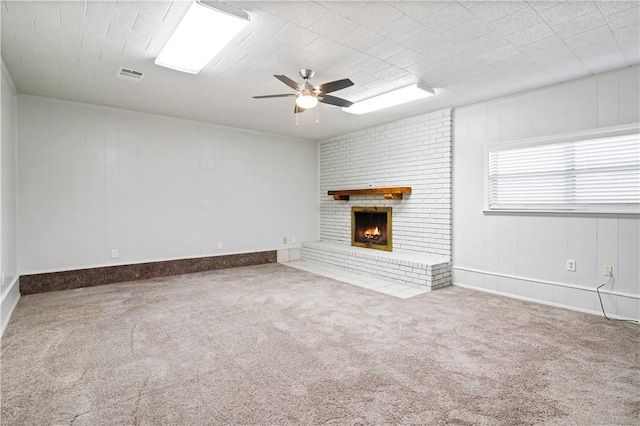unfurnished living room with a brick fireplace, visible vents, carpet flooring, and a ceiling fan
