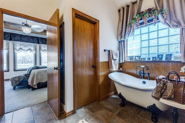 ensuite bathroom featuring ensuite bathroom, wood walls, a freestanding tub, and a wainscoted wall