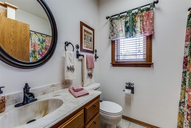 bathroom featuring toilet, baseboards, and vanity
