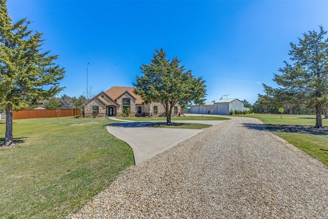 view of front of house featuring fence, a front lawn, brick siding, stone siding, and driveway