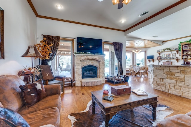 living room featuring visible vents, ornamental molding, wood finished floors, and a stone fireplace