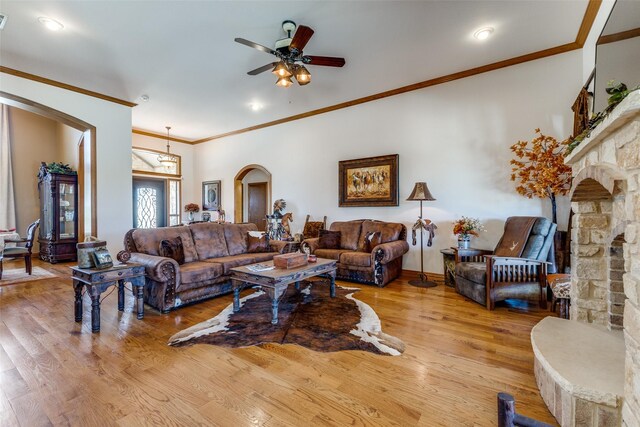living room featuring crown molding, arched walkways, a ceiling fan, and wood finished floors