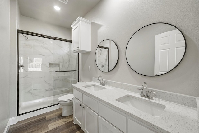 bathroom with a marble finish shower, a sink, toilet, and wood finished floors