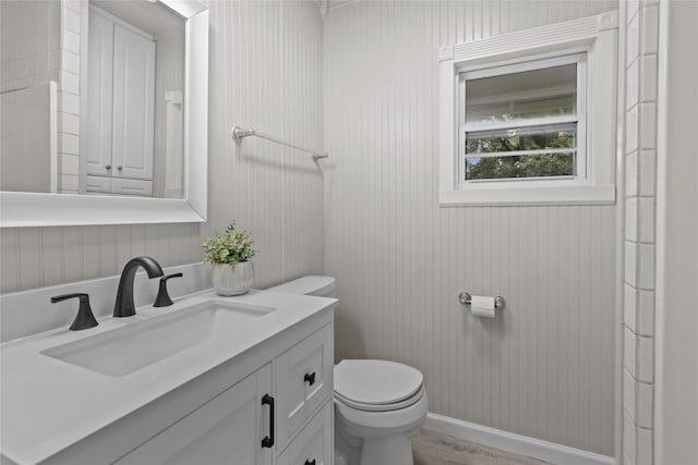 bathroom with toilet, vanity, and wood finished floors