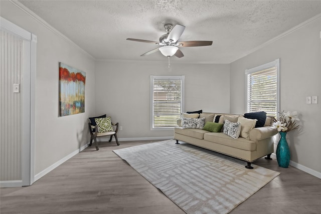 living area featuring a wealth of natural light, wood finished floors, a ceiling fan, and a textured ceiling