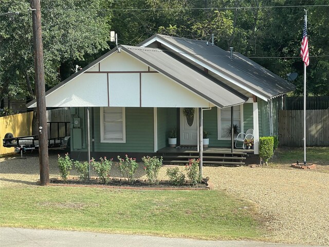 bungalow-style house featuring fence, covered porch, and a front yard