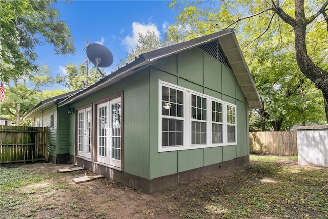 view of side of home with a storage unit, fence, an outbuilding, and crawl space