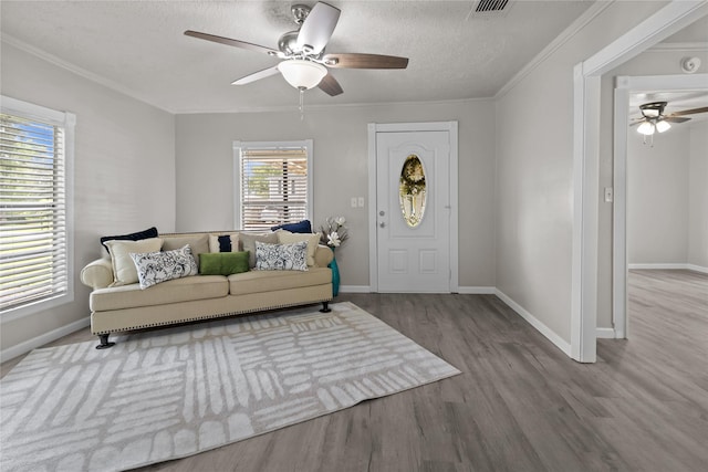 interior space with a textured ceiling, crown molding, visible vents, wood finished floors, and a ceiling fan