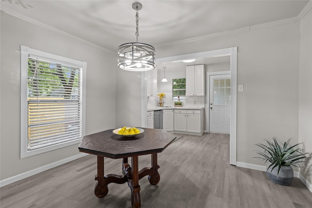 dining room with crown molding, light wood finished floors, a notable chandelier, and baseboards