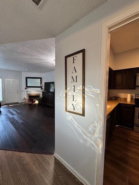 2411 Northlake Ct, Irving, TX 75038 - hallway featuring a textured ceiling, dark wood-style flooring, and baseboards