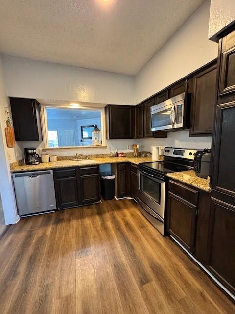 2411 Northlake Ct, Irving, TX 75038 - kitchen featuring appliances with stainless steel finishes, light countertops, dark wood-type flooring, dark brown cabinetry, and a textured ceiling